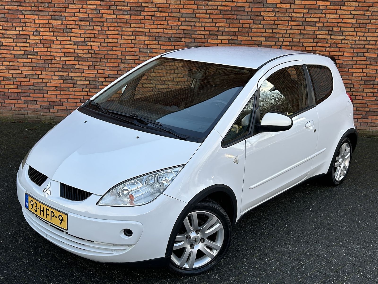 Witte Mitsubishi Colt voor de bakstenen muur
